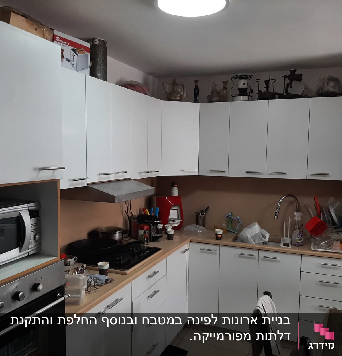 מטבח עם ארונות לבנים, תנור ומיקרוגל